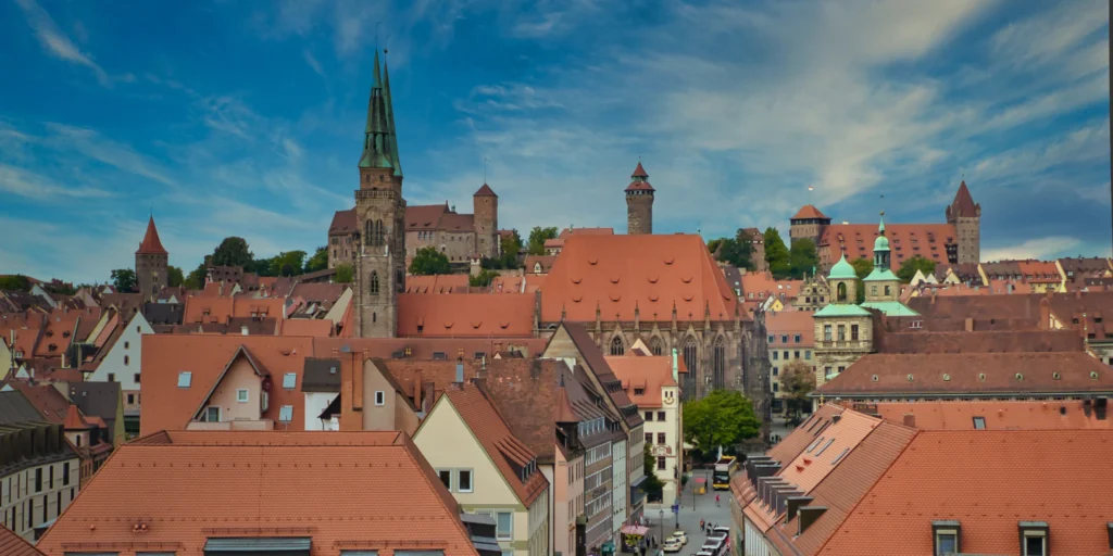 Blick über Nürnbergs Altstadt mit roten Dächern, Sebalduskirche und Kaiserburg unter bewölktem Himmel