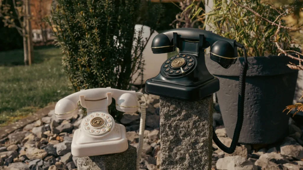 Zwei Retro-Telefone als Audio-Gästebuch auf Steinsäulen im Garten
