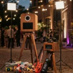 Fotobox im Holzdesign auf stilvoller Abendveranstaltung mit Lichterketten, Gästen und Partyrequisiten im Hintergrund