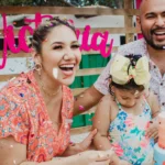 Fröhliche Familie feiert einen Kindergeburtstag im Garten mit bunter Geburtstagstorte, Konfetti und sommerlicher Partydekoration.
